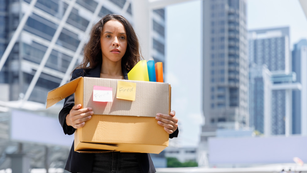 unhappy businesswoman carrying box of personal stuff out of office