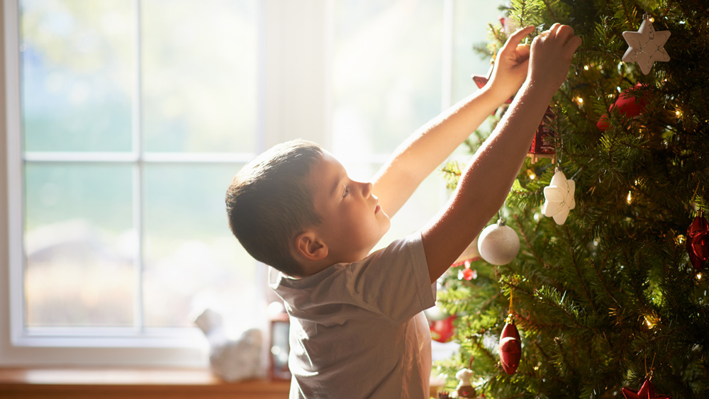 a young boy decorating christmas tree