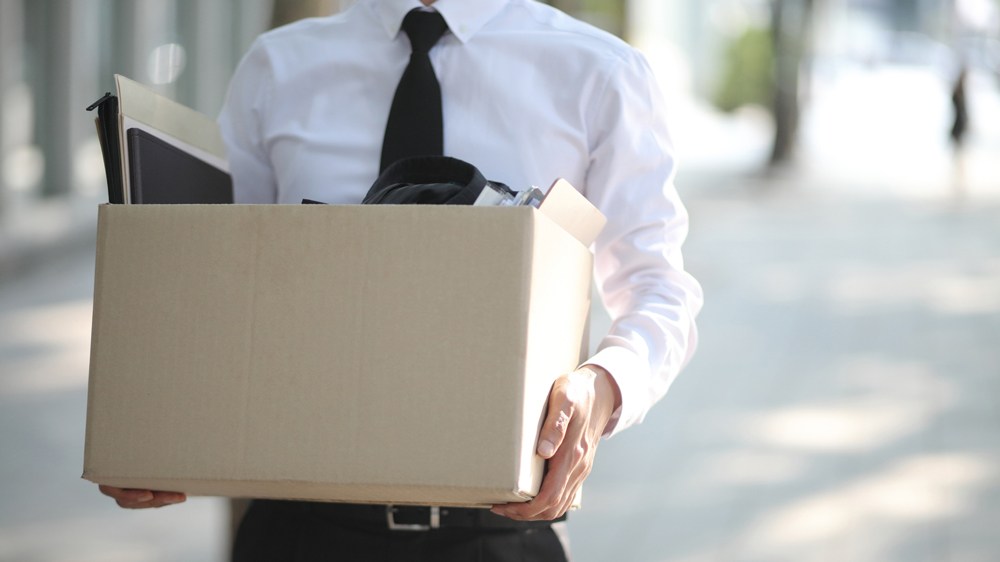 man carrying box of office stuff after getting let go