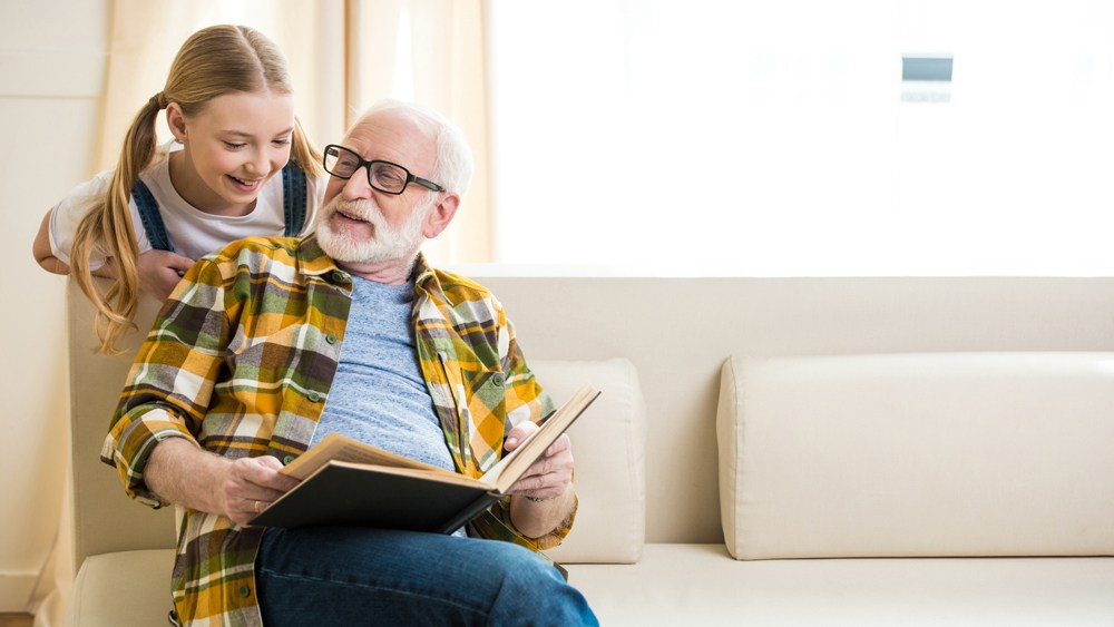grandfather and granddaughter looking a book together