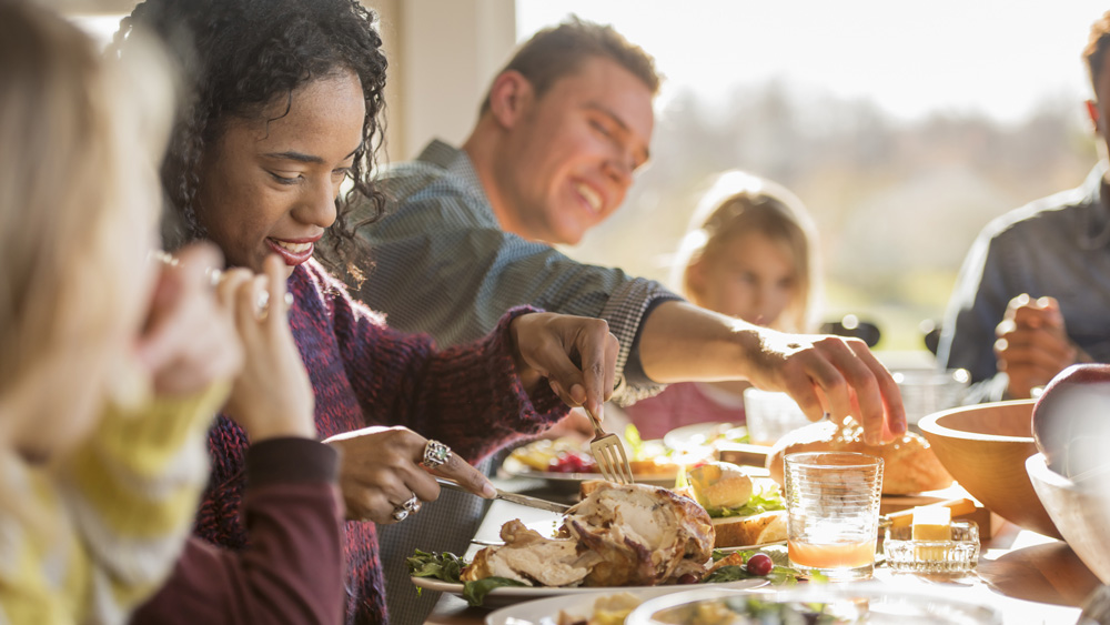 a group of adults and children sitting around dinner table for a holiday dinner