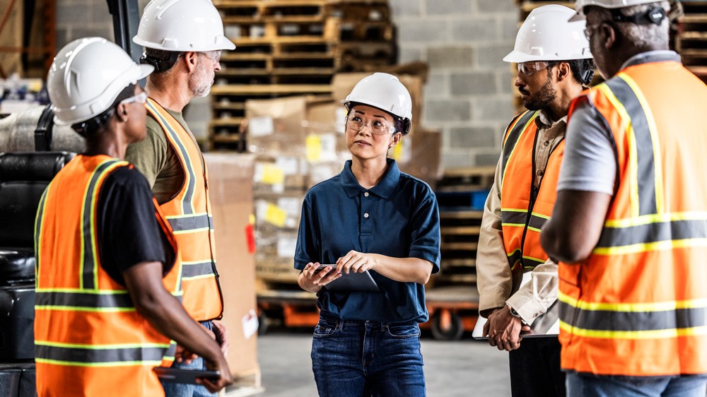 Female warehouse supervisor speaking with a group of employees