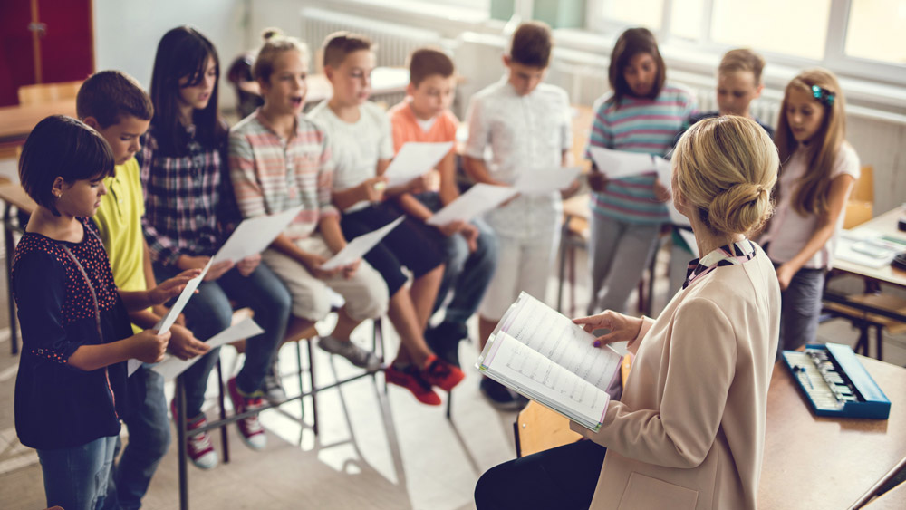 a female teacher directing young students learning to sing
