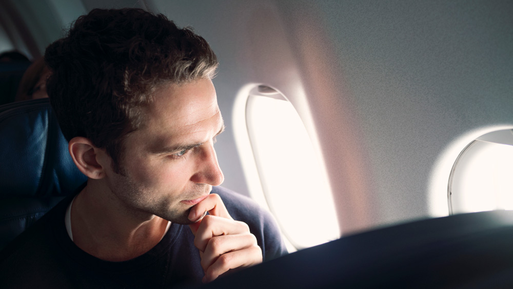 Thoughtful man looking through airplane window