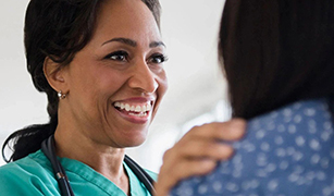 a nurse or doctor smiling and talking with a patient