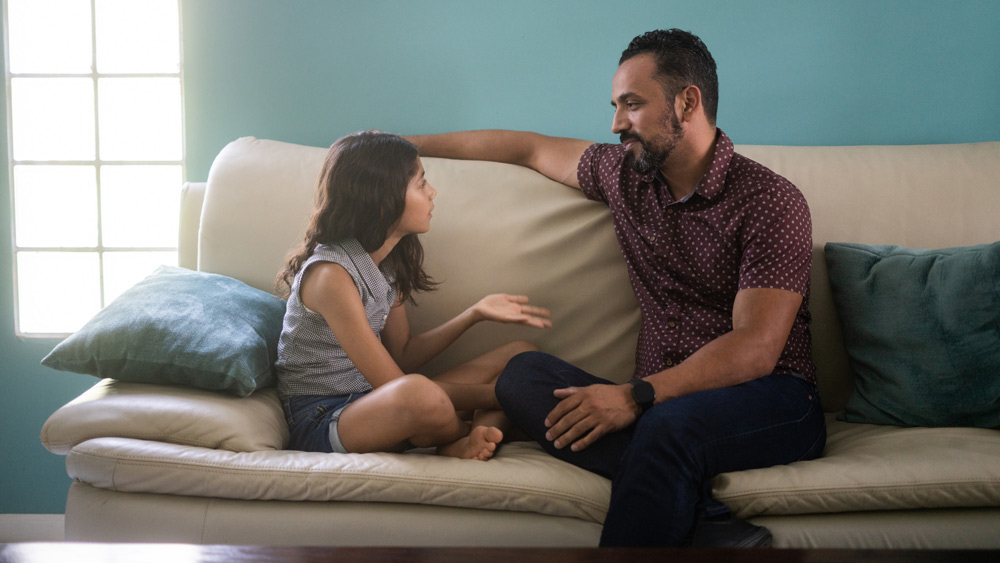 father and daughter sitting on couch talking