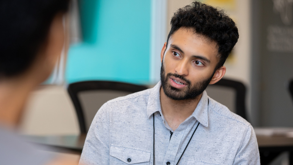 young man sitting in meeting with other people