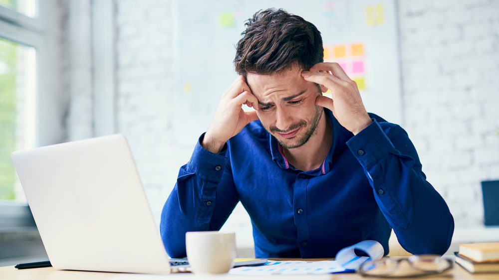 a man sitting at his desk looking sad, worried, and stressed