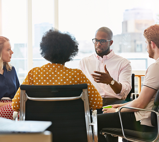 a man leading small group discussion in casual office environment