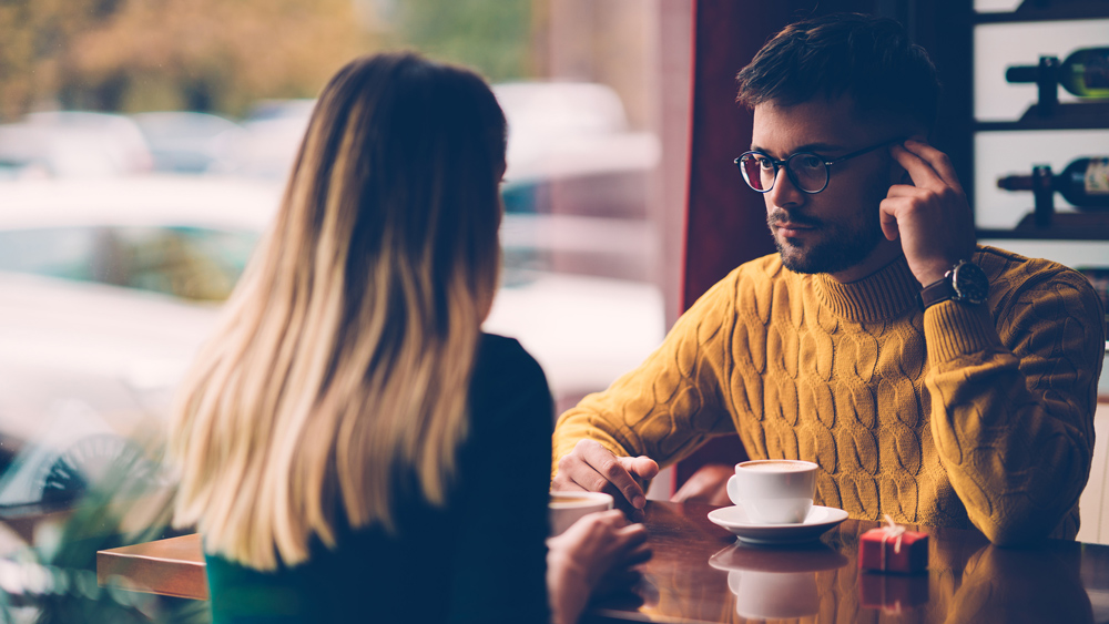 man and woman having a serious conversation over coffee