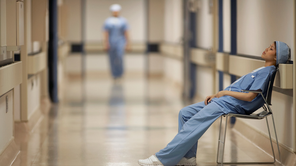 a nurse sleeping in chair with another nurse approaching