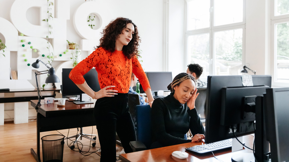 Business Manager Overlooking Colleague Working