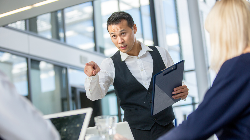 young executive pointing finger at employee in meeting