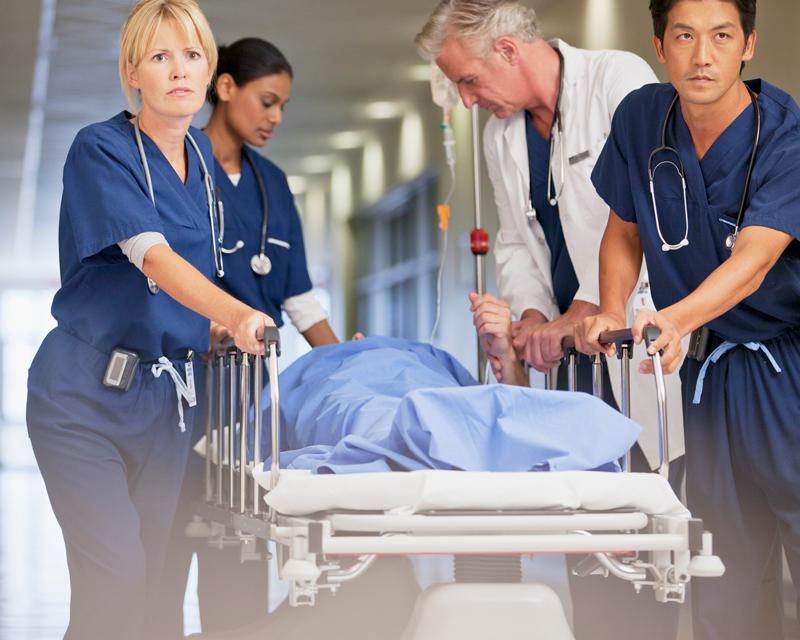 team of nurses and doctor with patient in tense moment
