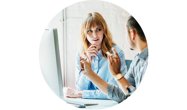 Two coworkers talking in front of a computer screen