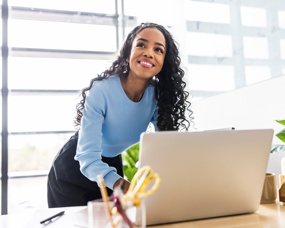 woman looking from computer to greet coworker